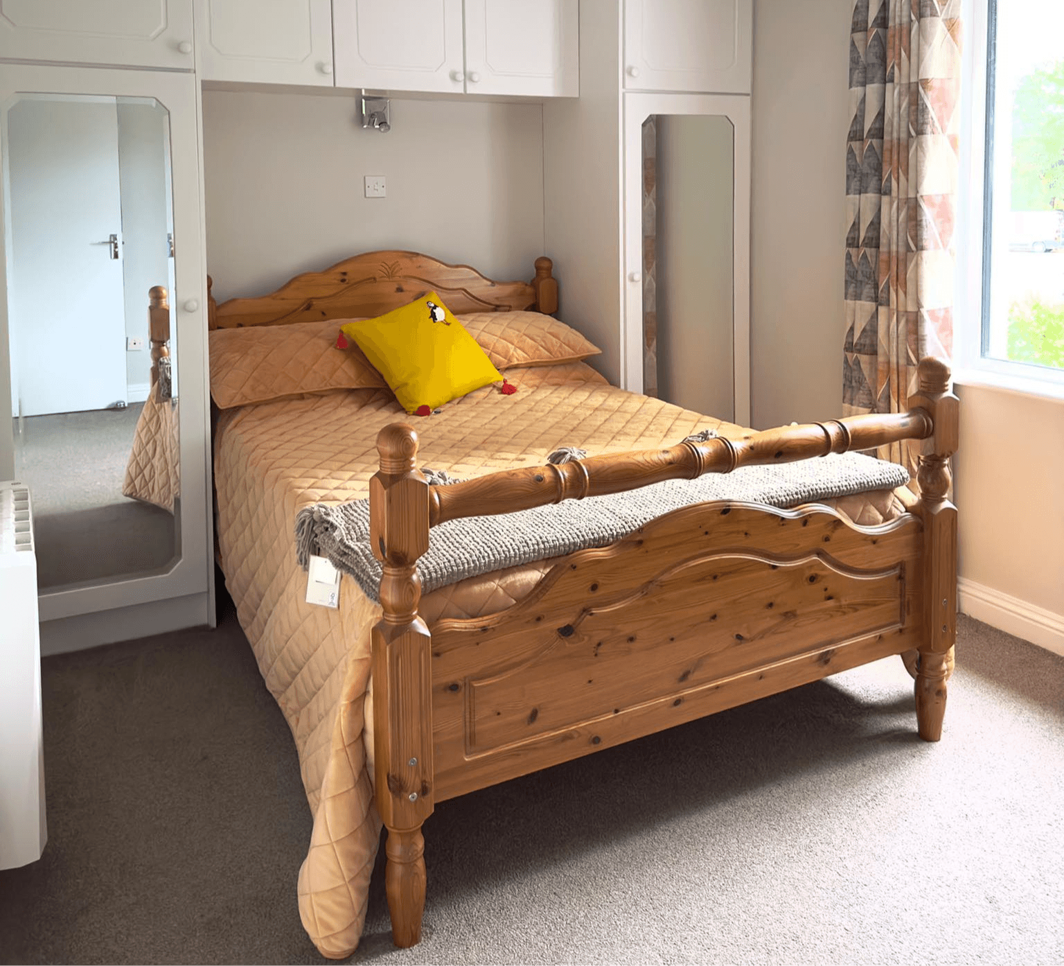 Double bedroom with pine bed frame and yellow cushion at Tully's Home
